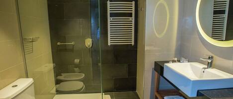 A modern bathroom with a glass-enclosed shower, a white toilet, a sink with a mirror, and a towel rack.