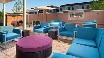 An outdoor seating area with blue and purple chairs, a round table, and a fire feature.