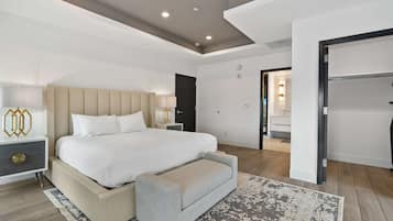 Una camera d'albergo moderna con un letto grande, comodini, una panca e vista sul bagno.