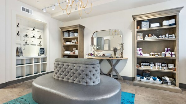 A well-organized room with a tufted ottoman, shelves with various products, a mirror, and a chandelier. - Embassy Suites by Hilton Knoxville Downtown (Knoxville)