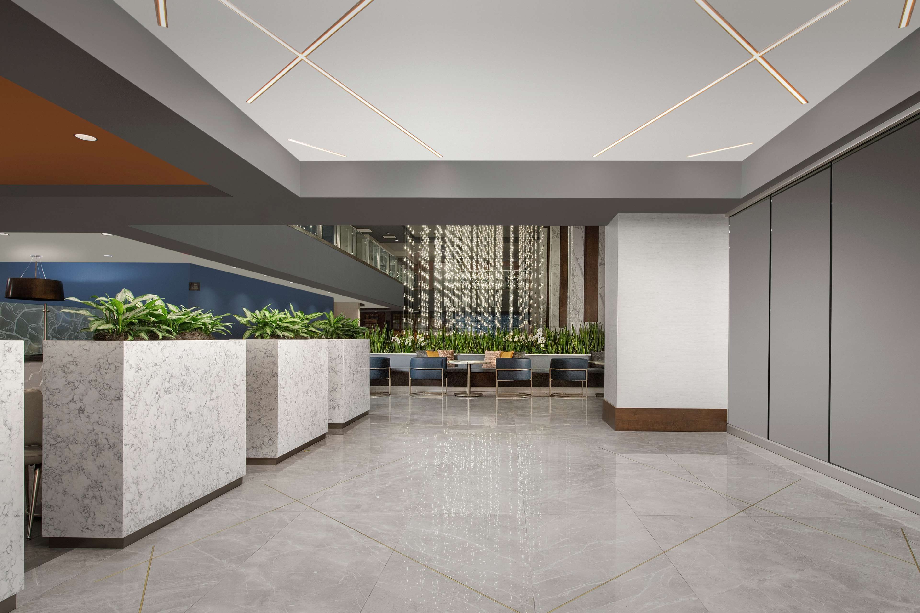 A modern lobby with marble reception counters, seating area, and a decorative wall with vertical elements.
