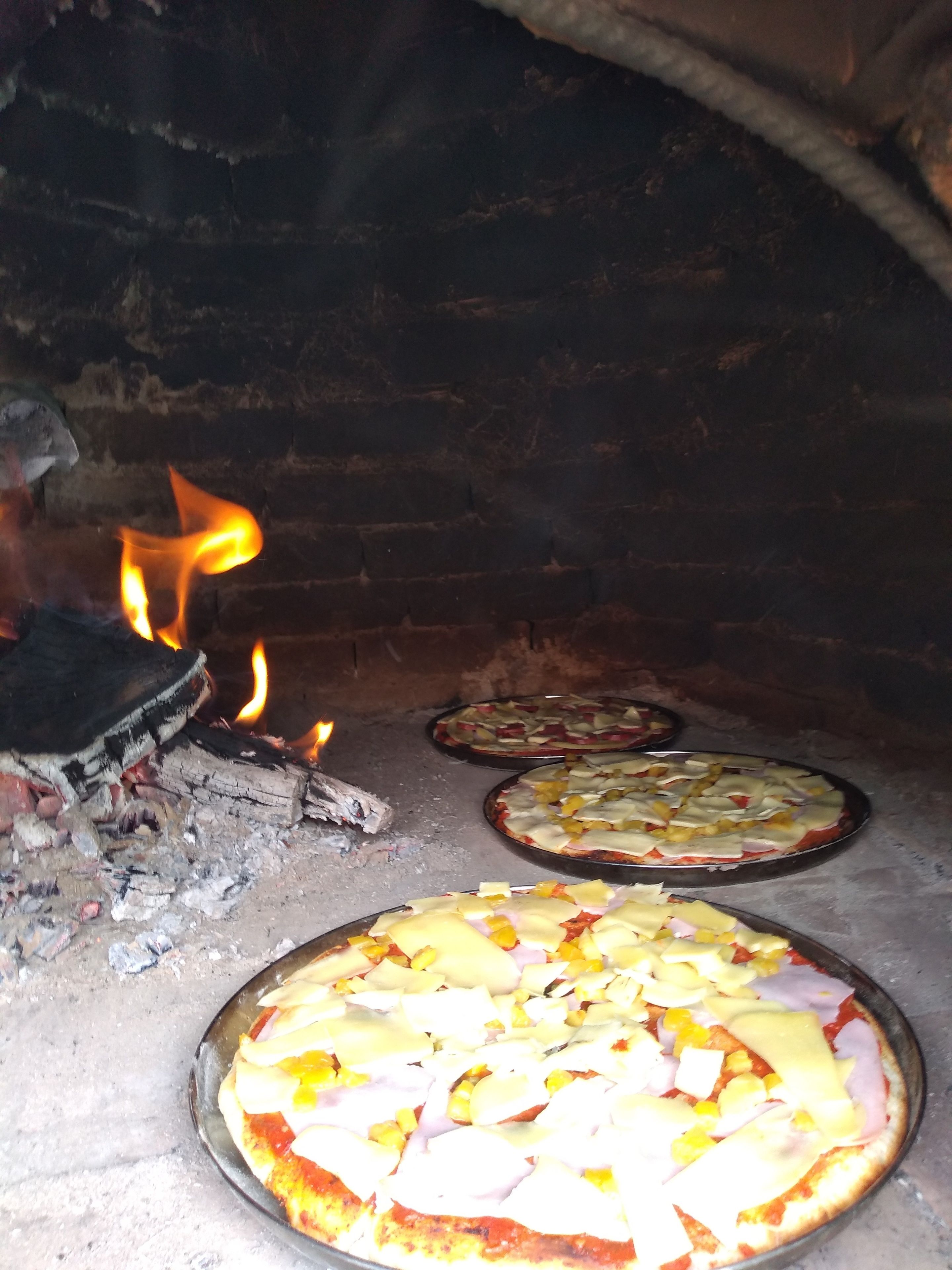 A pizza oven with three pizzas being cooked.