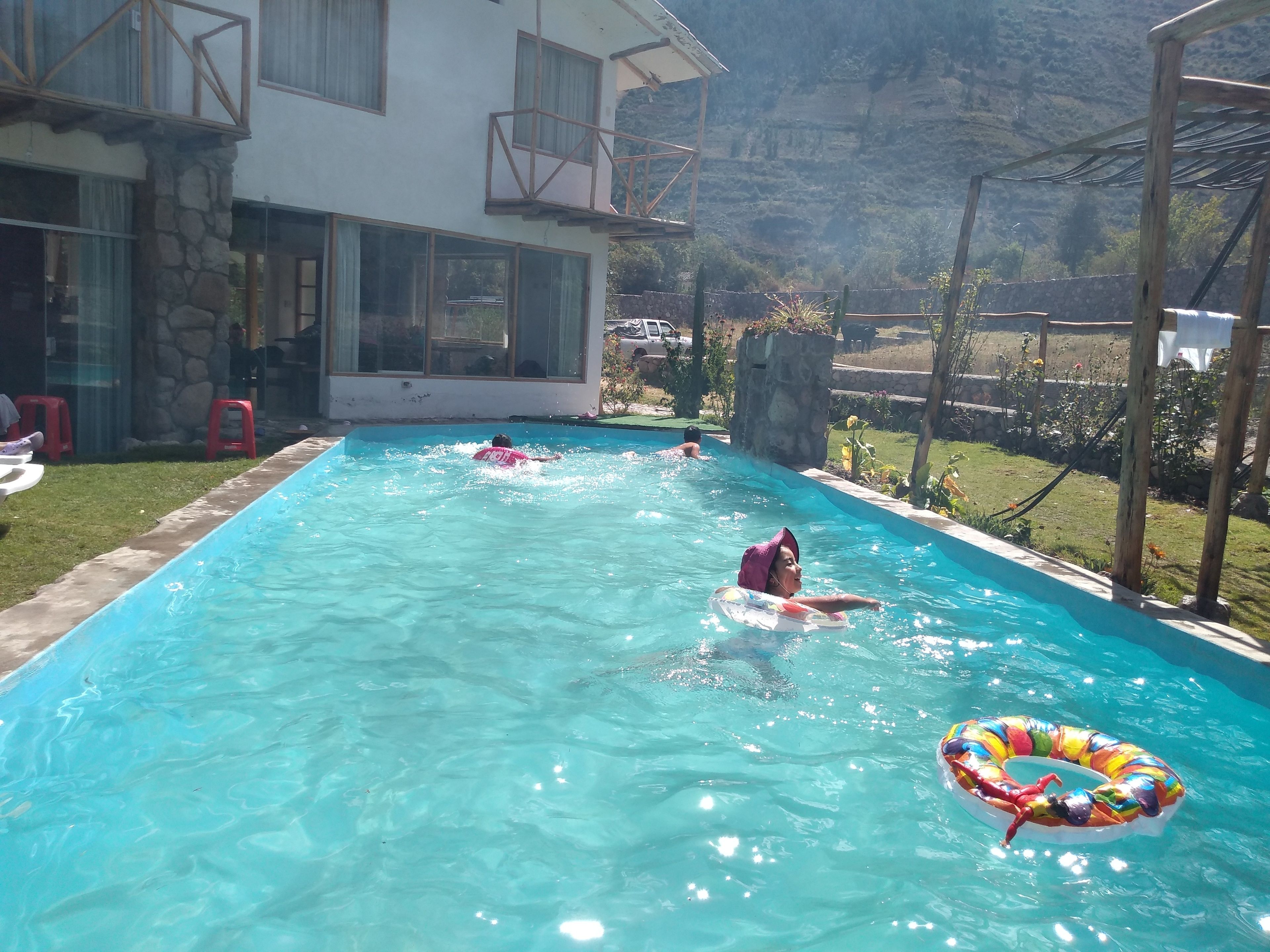 Una piscina con agua cristalina, rodeada por un muro de piedra y una terraza de madera.