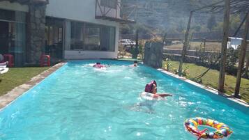 Una piscina con agua cristalina, rodeada por un muro de piedra y una terraza de madera.