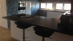 Una cucina moderna con una grande isola, sgabelli da bar, forno integrato e una finestra che offre luce naturale.