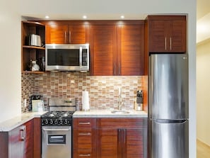 A modern kitchen with wooden cabinets, stainless steel appliances, and a tiled backsplash.
