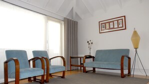 Une pièce avec deux fauteuils bleus, une table basse en bois et un lampadaire.