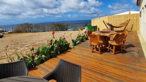 A wooden deck with outdoor furniture, a hammock, and a view of the beach and ocean. - Pousada Solar do Pico (Fernando de Noronha)