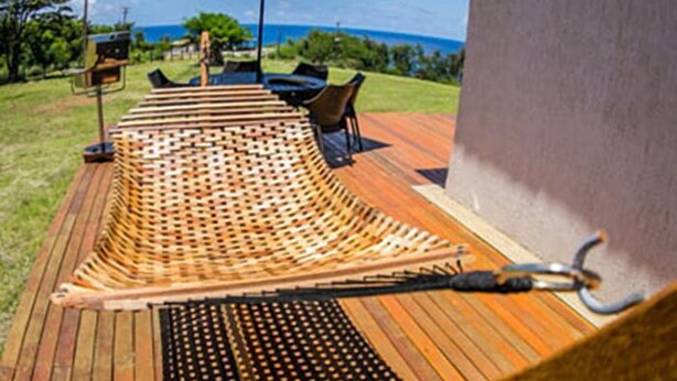 A wooden deck with a woven seating area, a table, and chairs. - Pousada Solar do Pico (Fernando de Noronha)