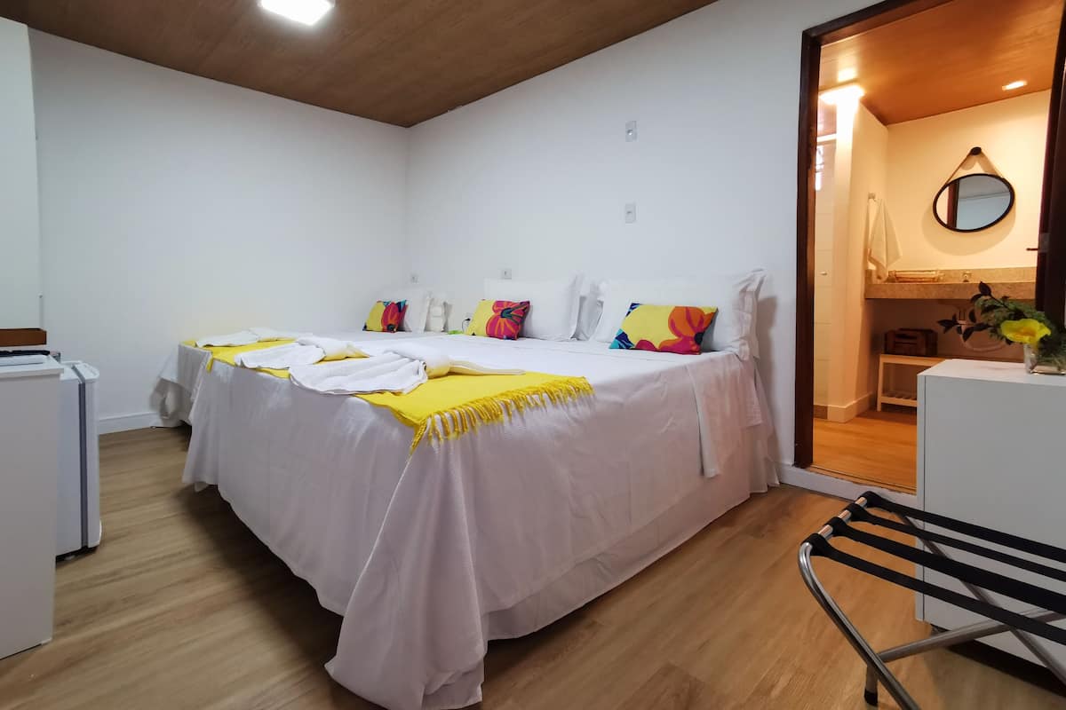 A hotel room with a bed, a chair, a desk, and a mirror.