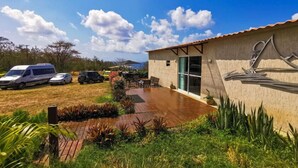 A building with a large patio area, a covered seating area, and a vehicle parked outside. - Pousada Solar do Pico (Fernando de Noronha)