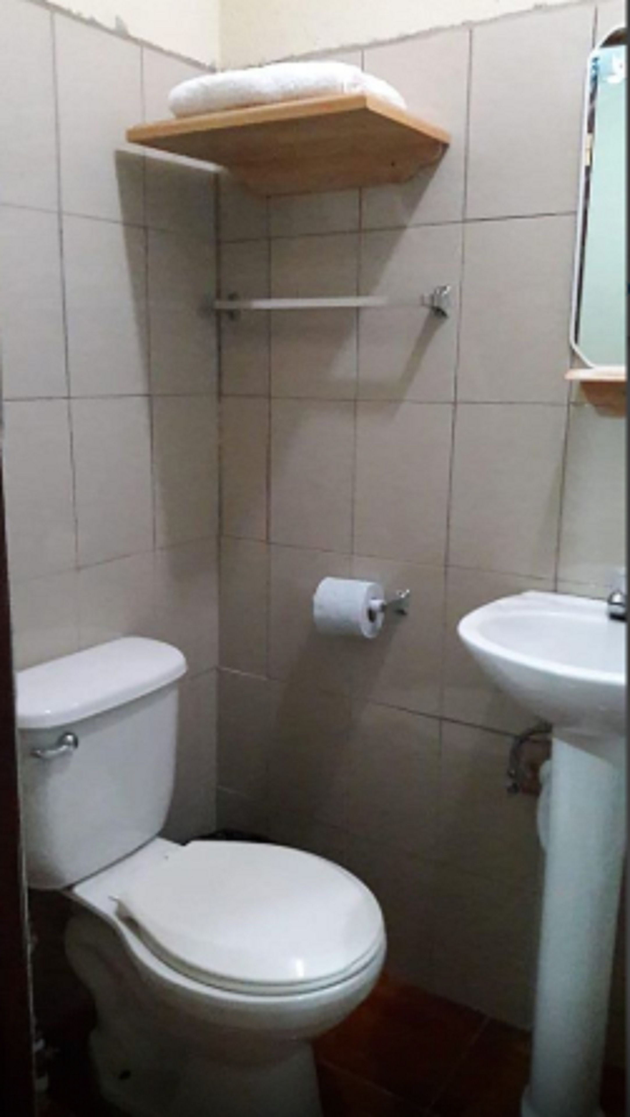 A small bathroom with a toilet, a sink, and a toilet paper holder on the wall.