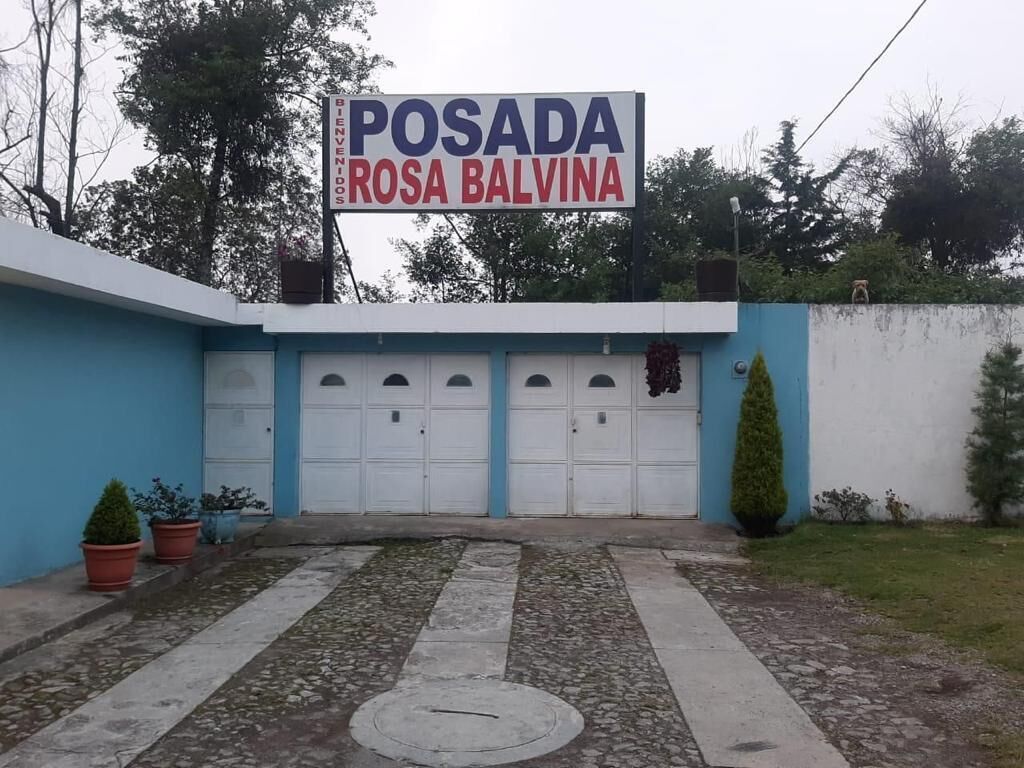 Um edifício com uma placa que diz "POSADA ROSA BALVINA" e uma garagem com quatro portas.