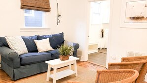 A living room with a dark blue sofa, white cushions, a small white table with a plant, and wicker chairs. - 2 Blocks to Mall - 8 Minute Walk to Beach (Cape May)