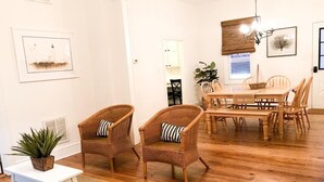A room with a wooden floor, two wicker chairs with striped cushions, a white table, and a dining table with chairs. - 2 Blocks to Mall - 8 Minute Walk to Beach (Cape May)