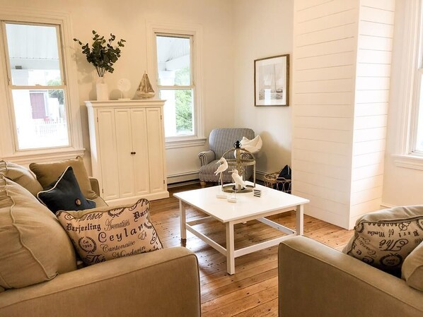 A cozy living room with a white coffee table, striped armchair, and beige sofas.