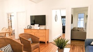 A living room with wicker furniture, a white coffee table, and a television on a dresser. - 2 Blocks to Mall - 8 Minute Walk to Beach (Cape May)