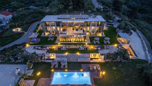 Una casa moderna de dos pisos con piscina, mobiliario exterior y senderos bien iluminados.