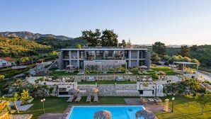 Un moderno resort con piscina, mobiliario exterior y vistas a las montañas.