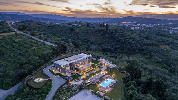 Una villa moderna con piscina, rodeada de exuberante vegetación y un camino sinuoso.
