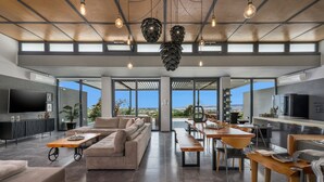 Amplia sala de estar con un sofá grande, una mesa de comedor y una zona de cocina con refrigerador y estufa.