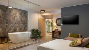 Un baño moderno con una bañera independiente, un espejo y un televisor montado en la pared.