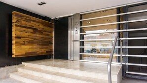 A modern entrance with a wooden wall, a glass door with a number 38, and a metal staircase. - Gente del Sur - Rivadavia (Ushuaia)