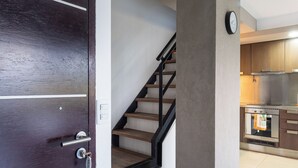 A modern kitchen with stainless steel appliances, a wooden staircase, and a dark wooden door. - Gente del Sur - Rivadavia (Ushuaia)