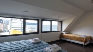 A bedroom with two beds, large windows, and a view of the sea. - Gente del Sur - Rivadavia (Ushuaia)