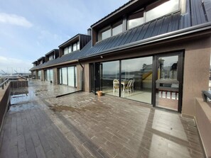 A modern building with a flat roof, large glass windows, and a wooden deck. - Gente del Sur - Rivadavia (Ushuaia)