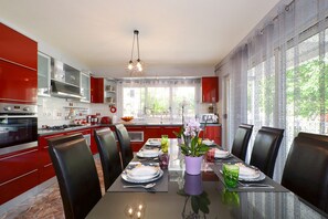 Een moderne keuken met rode kasten, een eettafel gedekt voor zes personen en een groot raam met uitzicht op groen.