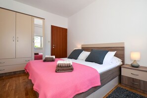 Een slaapkamer met een bed, nachtkastje, lamp, kledingkast en spiegel.