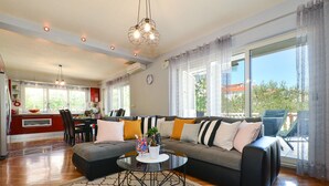 Een ruime woonkamer met een grote bank, een salontafel en een eethoek op de achtergrond.