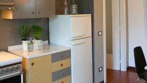 Une cuisine compacte dotée d’un four encastré, d’un réfrigérateur et d’un petit plan de travail.