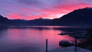 Un lago tranquillo con montagne sullo sfondo e un molo con barche.