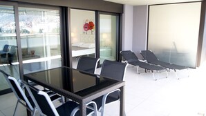 A modern room with a glass partition, a dining table with chairs, and two lounge chairs. - City center with stunning lake views. 405 (locarno)