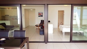 A modern hotel room with a glass door leading to a balcony, a white bed, a small desk, and a chair. - City center with stunning lake views. 405 (locarno)