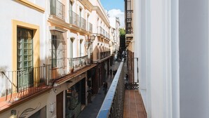 A narrow street with buildings on either side, featuring balconies and storefronts. - Hommyhome Casa Assle 101 (Sevilla)