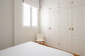 Une chambre à coucher avec un lit, une chaise et une grande armoire.