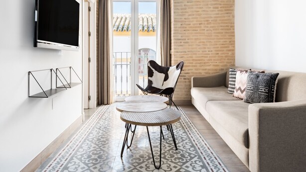 Un salon moderne avec un téléviseur à écran plat, un canapé agrémenté de coussins à motifs, une table à manger et une chaise.