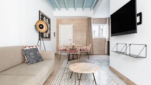 Un salon moderne avec un canapé, un tapis à motifs et un coin repas comprenant des chaises et une table.