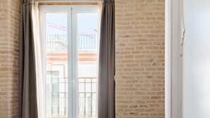 Une chambre avec un lit, une fenêtre avec des rideaux et une vue sur un balcon.