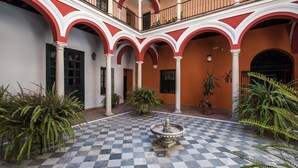 A courtyard with a checkered floor, red and white arches, and a central fountain. - Hommyhome San Isidoro Loft (Seville)