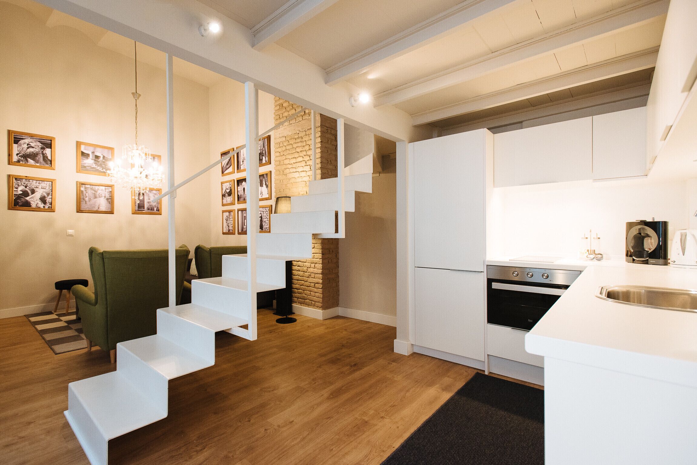 A modern kitchen with white cabinetry, a built-in oven, and a stainless steel sink.