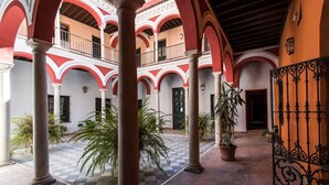 Un patio con arcos, columnas y plantas en macetas.