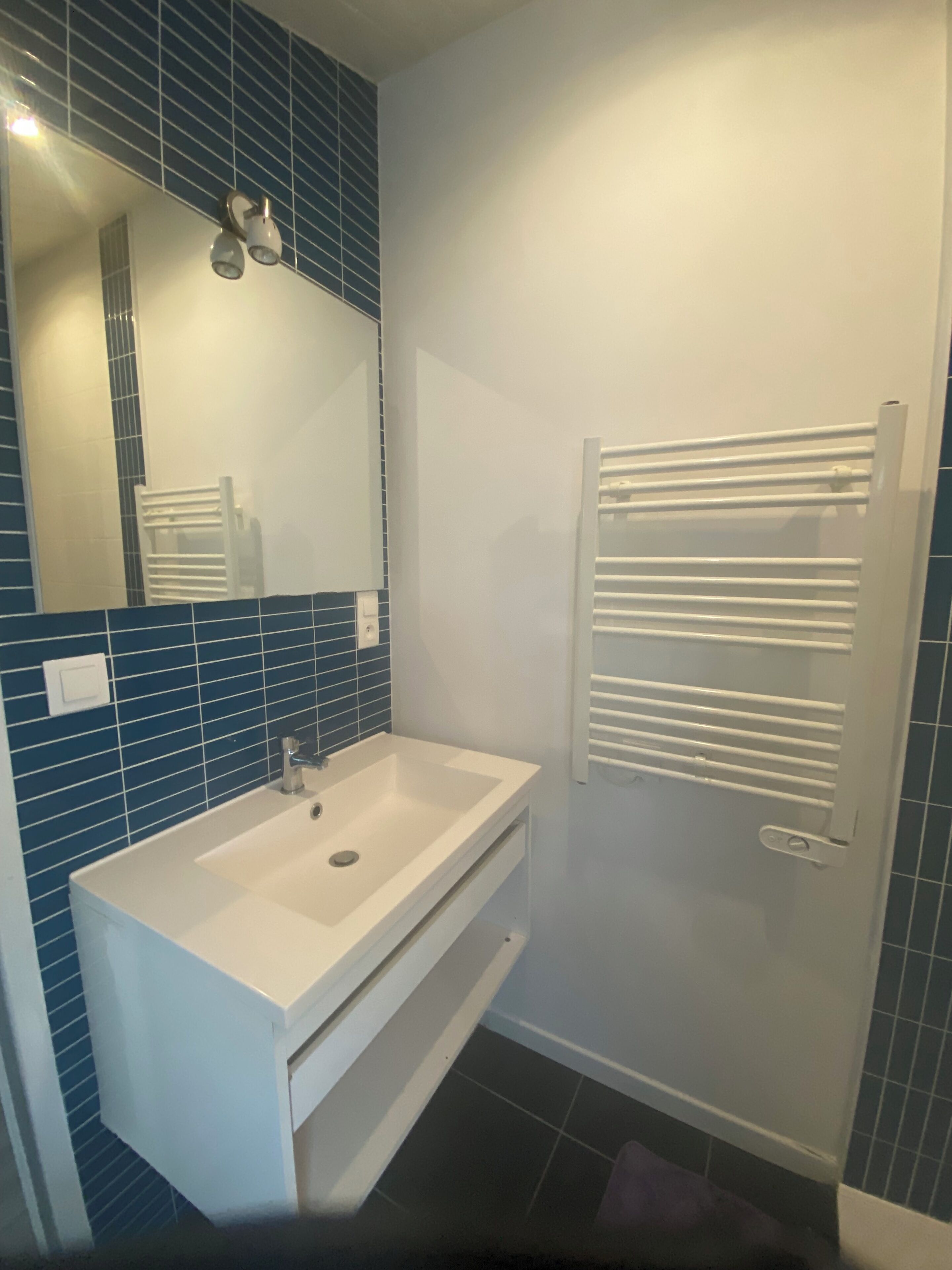 A bathroom with a white sink, a mirror, and a towel rack.