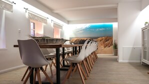 Un comedor con una larga mesa, varias sillas y vista a una playa a través de un ventanal amplio.