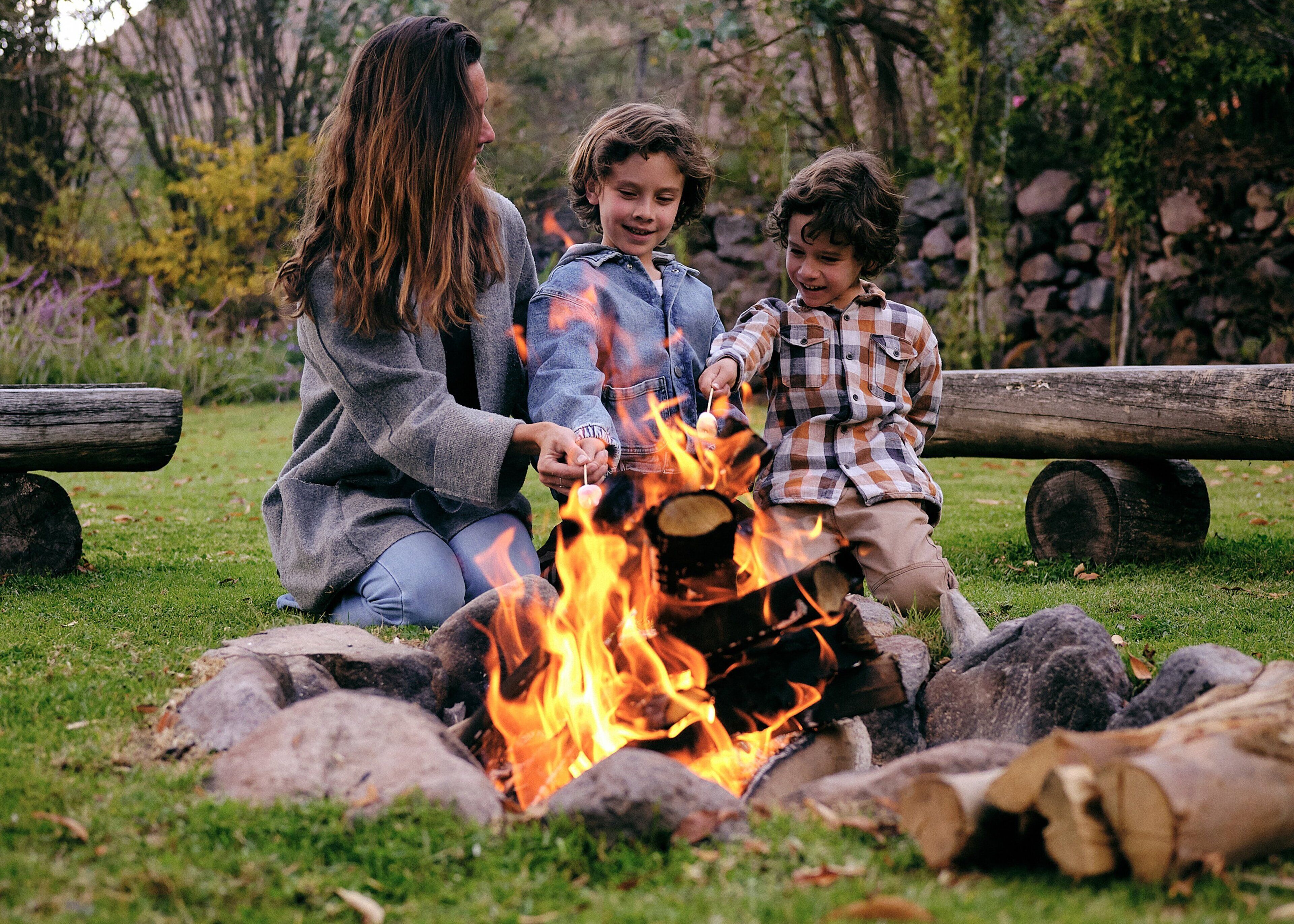 A family around a campfire in a grassy outdoor setting.