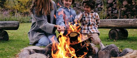 A family around a campfire in a grassy outdoor setting.