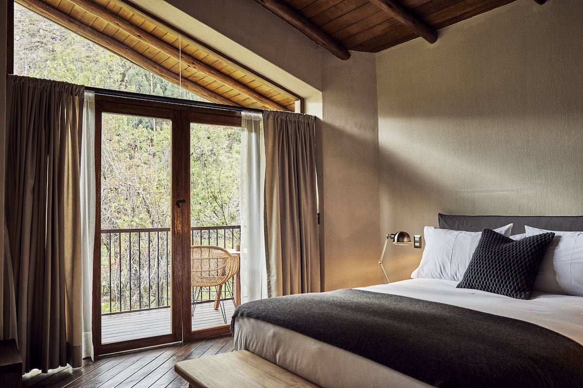 A bedroom with a bed, a nightstand, a lamp, and a view of the outdoors through a sliding door.